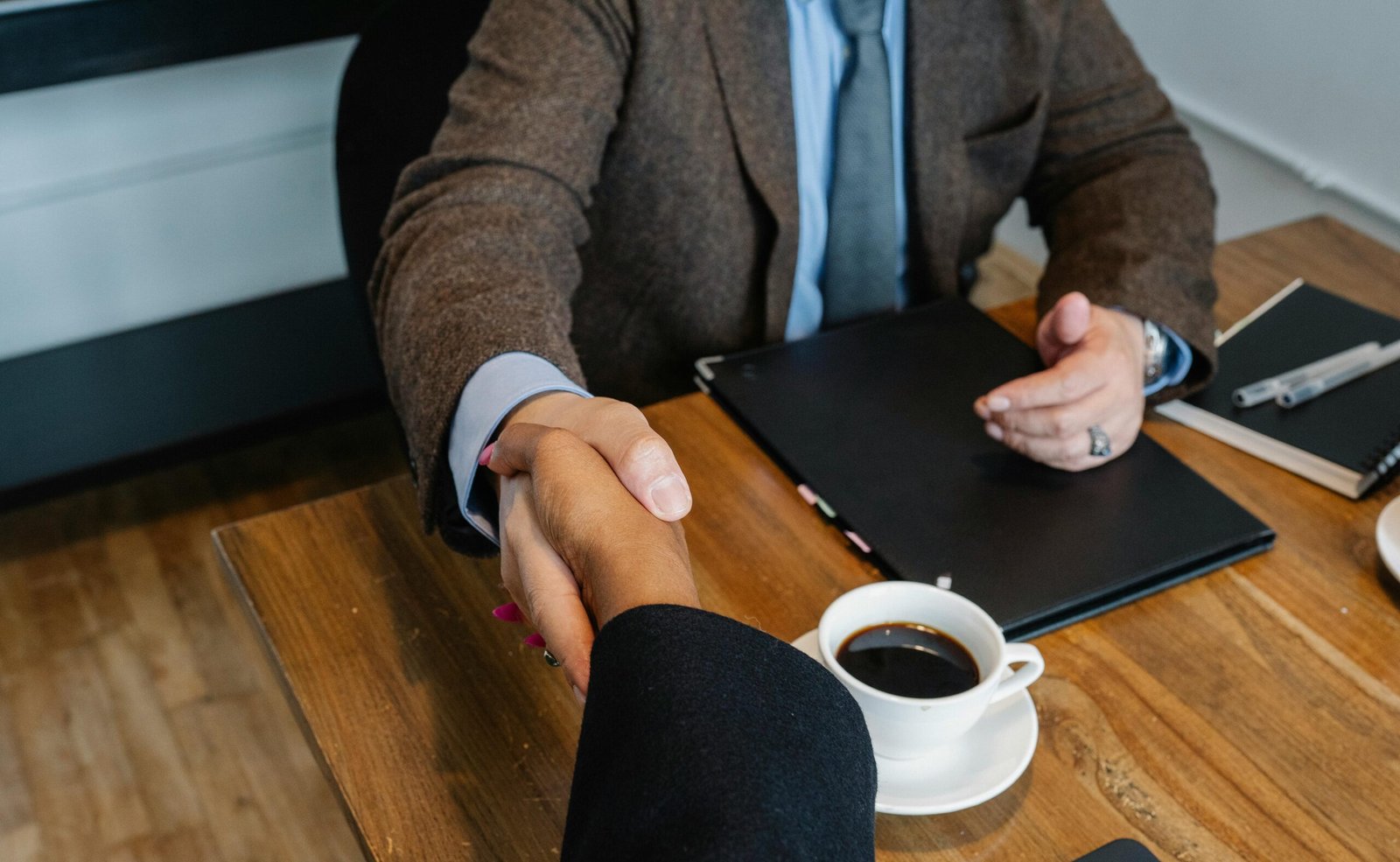 Professional handshake between colleagues at an office meeting with coffee.
