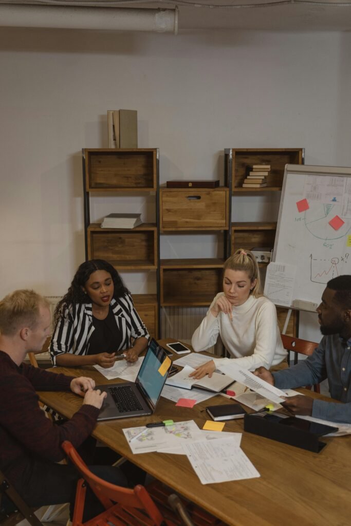 A diverse team engaged in a project discussion around a table in a modern office setting.